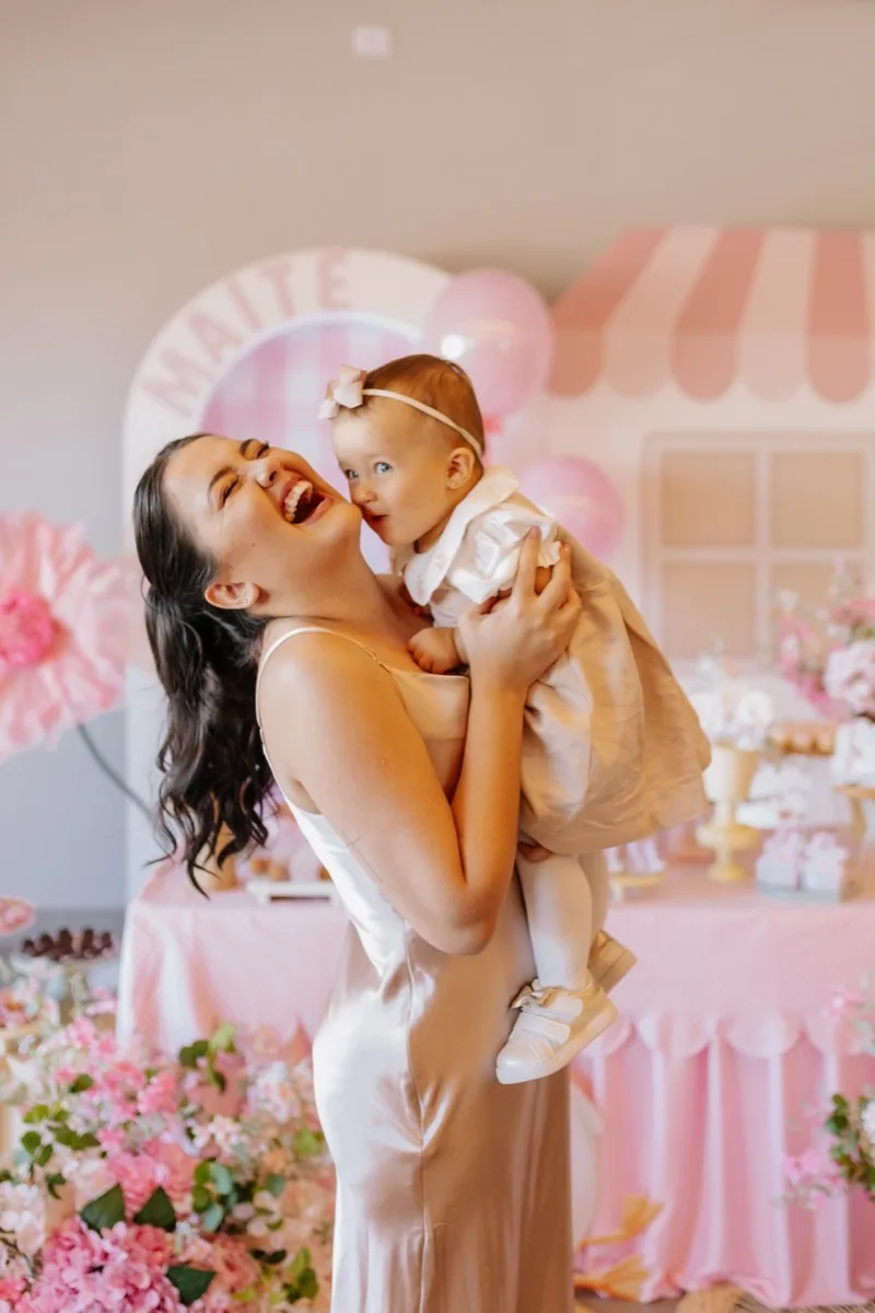 Mãe sorrindo com bebê no colo em festa infantil - Camila Barradas Fotografia